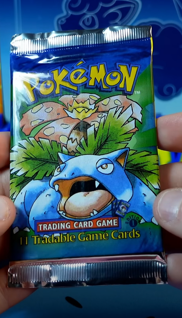 Hands holding a 1st Edition Base Set booster pack